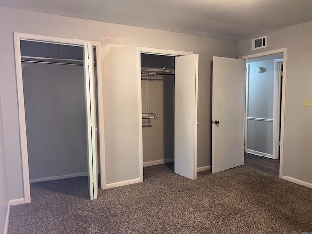 unfurnished bedroom with two closets and dark colored carpet