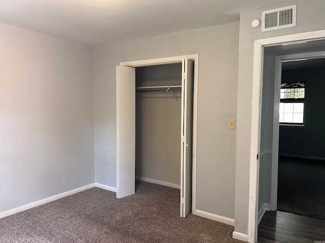 unfurnished bedroom with a closet and dark carpet