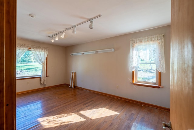 spare room featuring a healthy amount of sunlight, hardwood / wood-style floors, and rail lighting