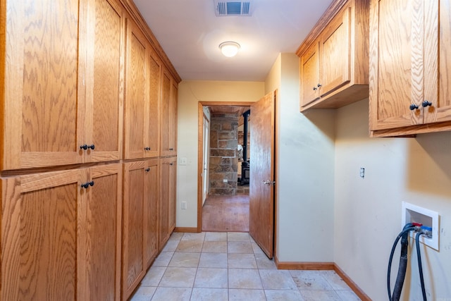 clothes washing area with hookup for a washing machine, cabinets, and light tile patterned floors