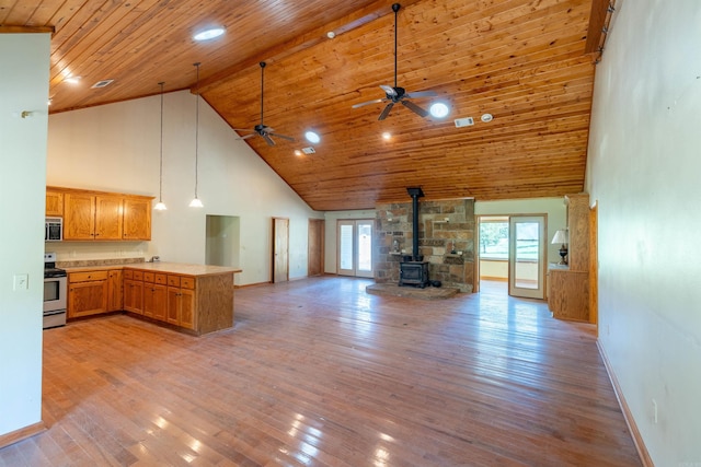 kitchen with high vaulted ceiling, wood ceiling, a wood stove, light hardwood / wood-style floors, and kitchen peninsula