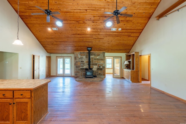 unfurnished living room with ceiling fan, a wood stove, high vaulted ceiling, wooden ceiling, and hardwood / wood-style floors