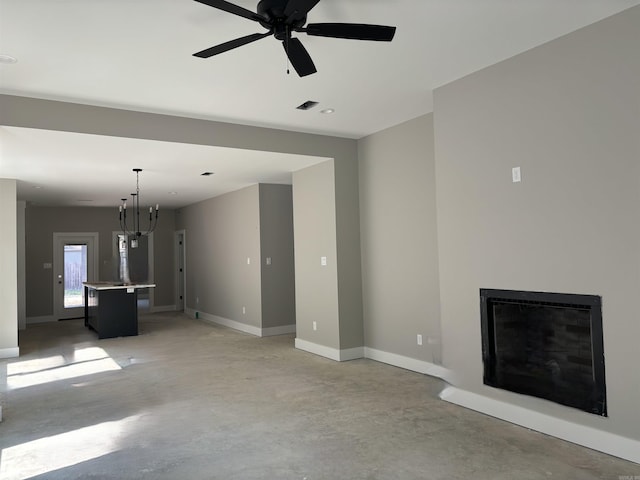 unfurnished living room with ceiling fan with notable chandelier and concrete floors