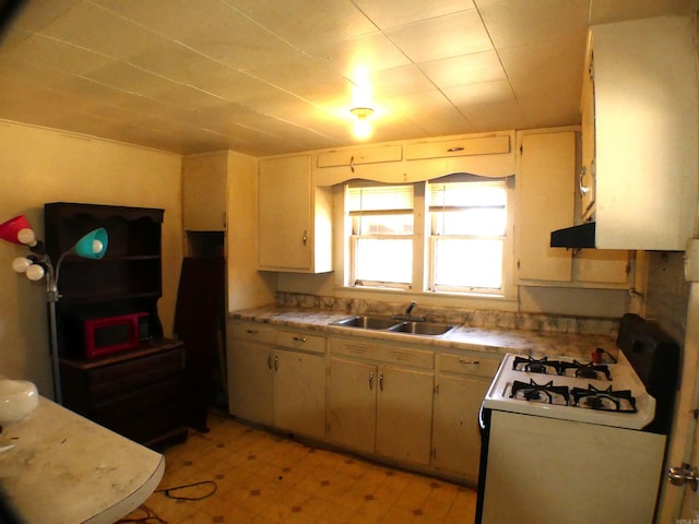 kitchen with a sink, light countertops, white gas stove, and light floors