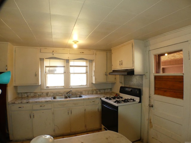 kitchen with a sink, under cabinet range hood, white gas range, and light countertops