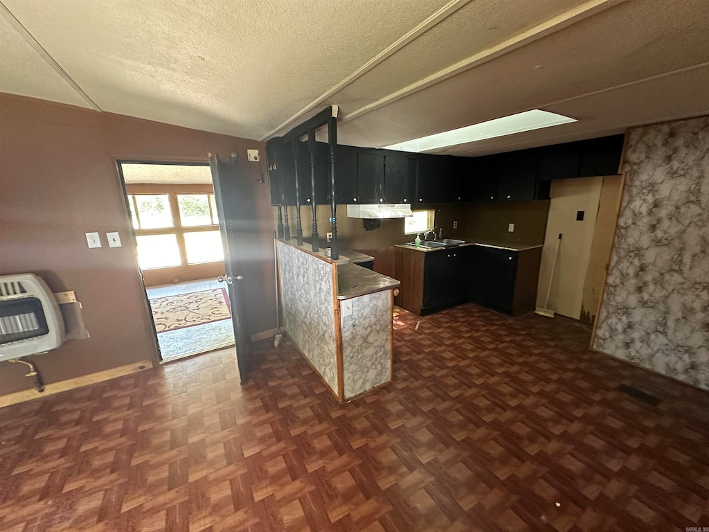 kitchen featuring lofted ceiling, sink, dark parquet floors, heating unit, and a textured ceiling