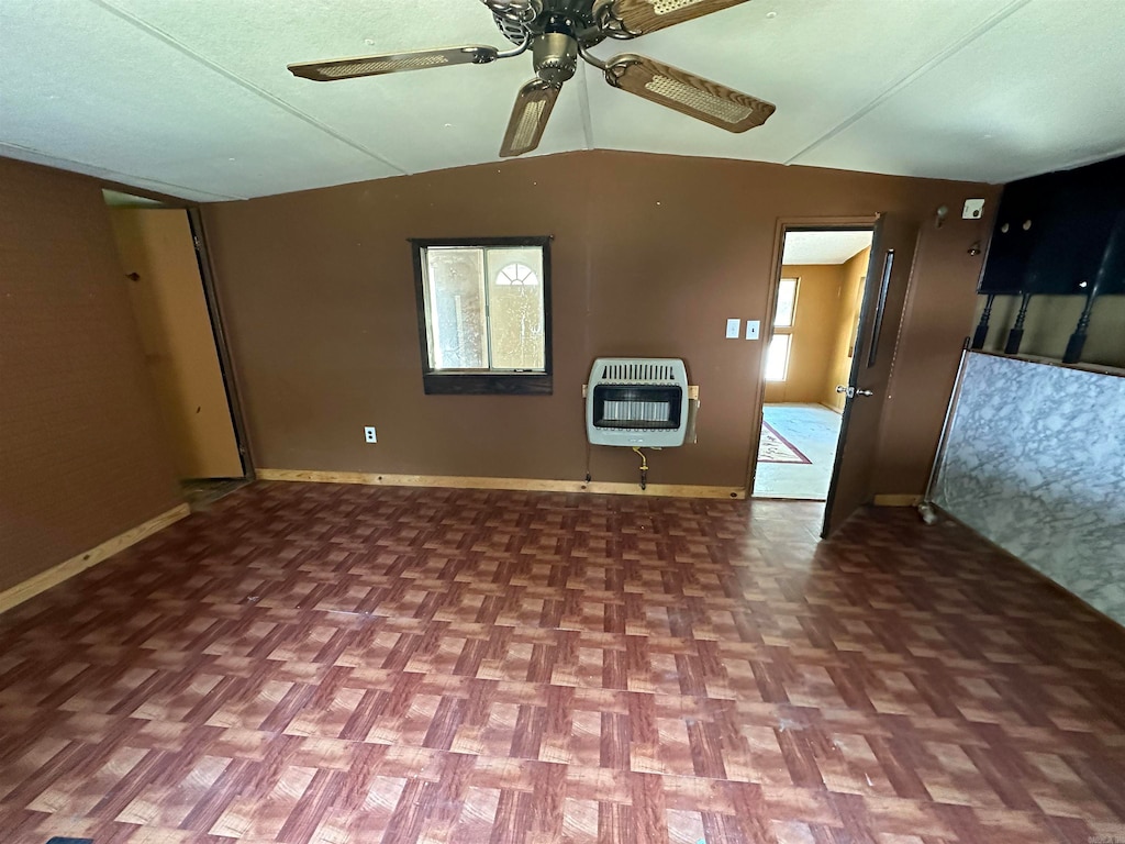 unfurnished living room with heating unit, vaulted ceiling, and ceiling fan