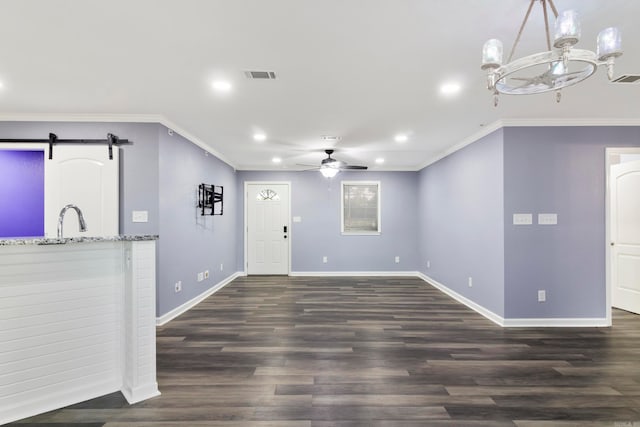 interior space with ornamental molding, ceiling fan with notable chandelier, a barn door, and dark hardwood / wood-style flooring