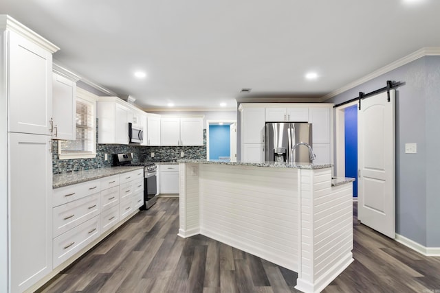 kitchen featuring stainless steel appliances, dark hardwood / wood-style floors, white cabinets, and a barn door