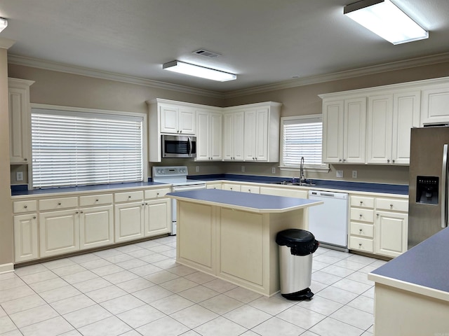 kitchen with ornamental molding, appliances with stainless steel finishes, a center island, and white cabinetry