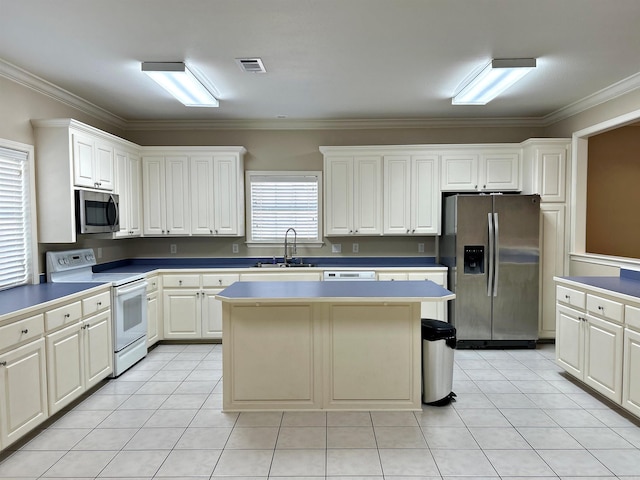 kitchen featuring a kitchen island, stainless steel appliances, sink, white cabinetry, and ornamental molding