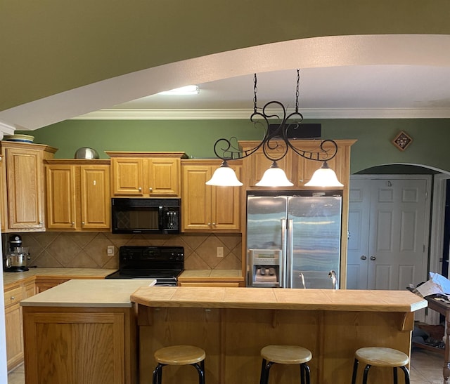 kitchen with a kitchen bar, pendant lighting, a center island, and black appliances