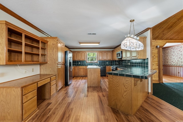 kitchen with light wood-type flooring, sink, kitchen peninsula, hanging light fixtures, and appliances with stainless steel finishes