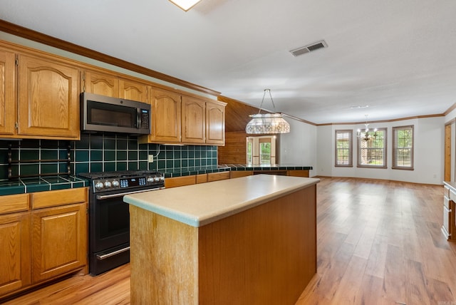 kitchen with light hardwood / wood-style floors, stove, crown molding, a notable chandelier, and a center island