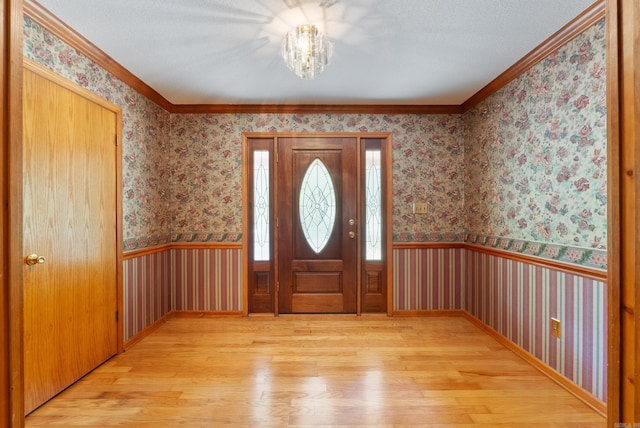 entrance foyer featuring a notable chandelier, crown molding, and light hardwood / wood-style floors