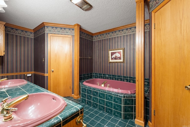 bathroom featuring a textured ceiling, tile patterned floors, sink, and tiled bath