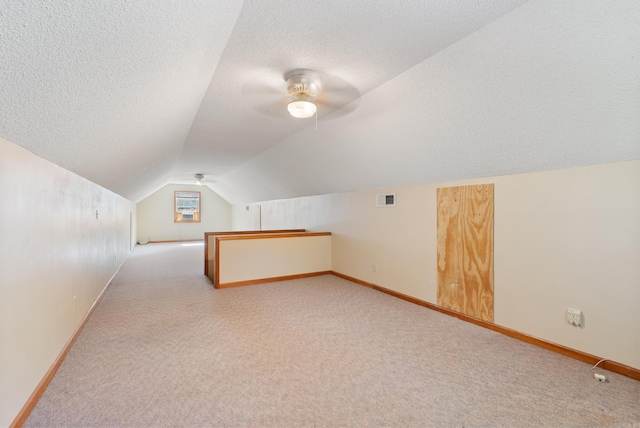 bonus room with ceiling fan, light colored carpet, a textured ceiling, and vaulted ceiling