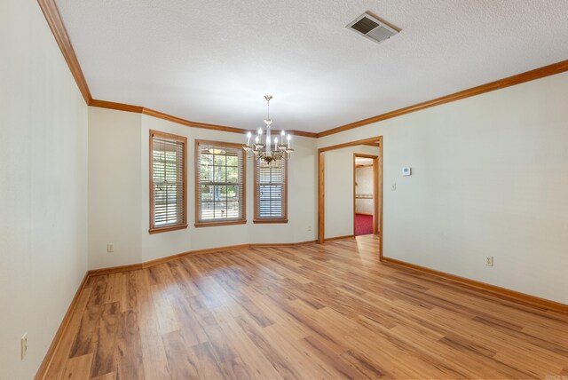 unfurnished room with a textured ceiling, a notable chandelier, ornamental molding, and light hardwood / wood-style flooring