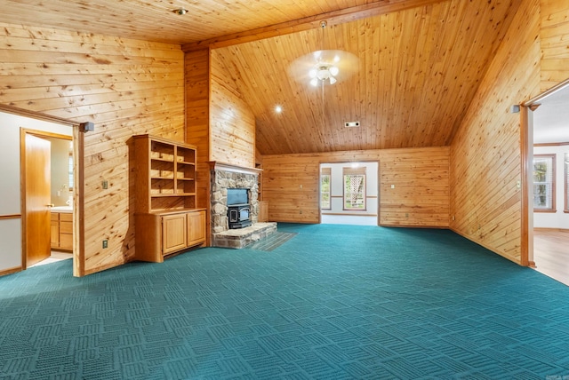 unfurnished living room with wood walls, carpet flooring, a wood stove, and wooden ceiling