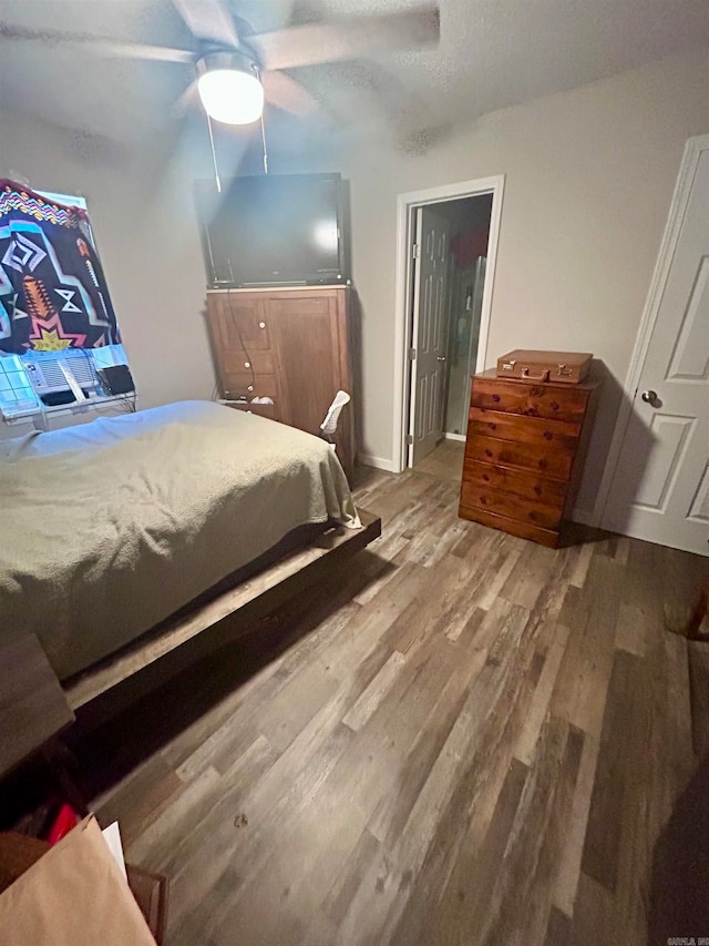 bedroom with ceiling fan, a textured ceiling, and hardwood / wood-style floors