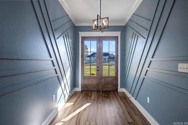 entryway with dark wood-type flooring, french doors, crown molding, and a notable chandelier