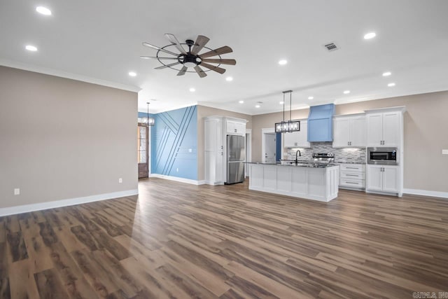 kitchen with a center island with sink, stainless steel appliances, dark hardwood / wood-style flooring, and white cabinetry