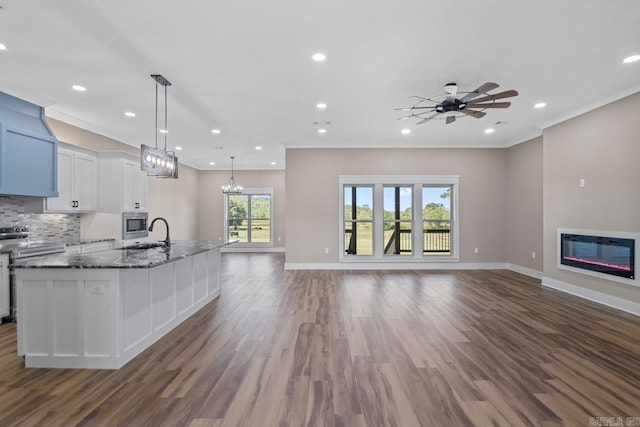 kitchen with hanging light fixtures, a center island with sink, dark hardwood / wood-style flooring, and white cabinetry