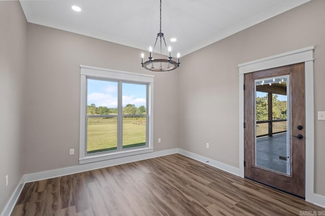 unfurnished dining area with ornamental molding, a notable chandelier, and hardwood / wood-style floors