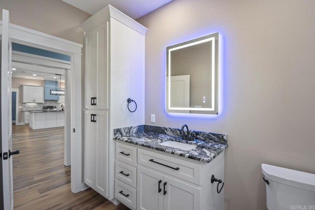 bathroom with hardwood / wood-style flooring, vanity, and toilet