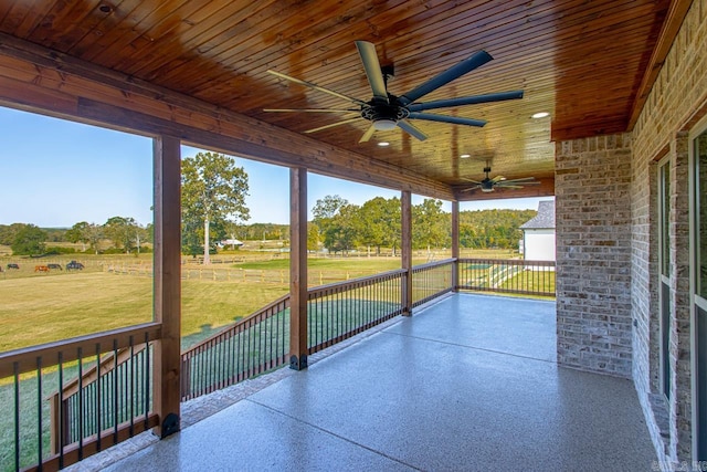 unfurnished sunroom featuring ceiling fan, a rural view, and wood ceiling