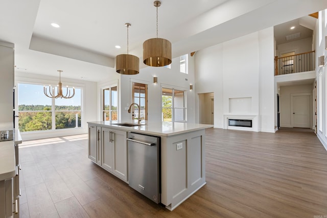 kitchen featuring hanging light fixtures, sink, stainless steel dishwasher, a kitchen island with sink, and dark hardwood / wood-style flooring