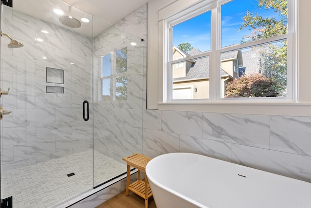 bathroom with separate shower and tub, tile walls, and a healthy amount of sunlight