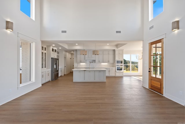 kitchen with white cabinets, sink, light hardwood / wood-style floors, a high ceiling, and appliances with stainless steel finishes