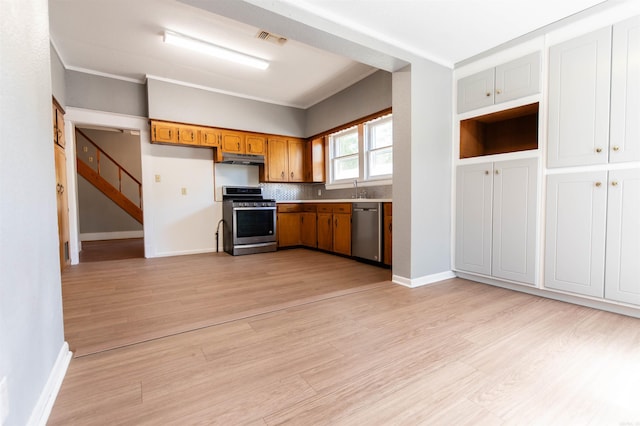 kitchen featuring ornamental molding, sink, tasteful backsplash, appliances with stainless steel finishes, and light hardwood / wood-style floors