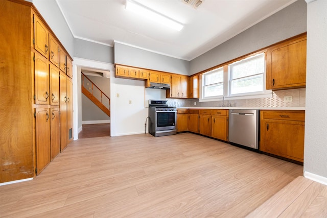 kitchen with stainless steel appliances, backsplash, crown molding, and light hardwood / wood-style flooring