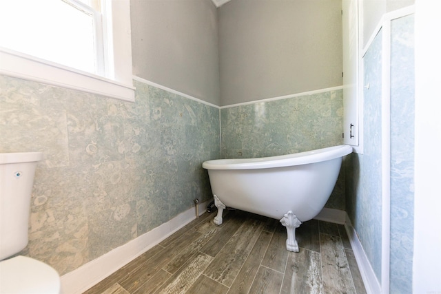 bathroom featuring a bath, toilet, and wood-type flooring