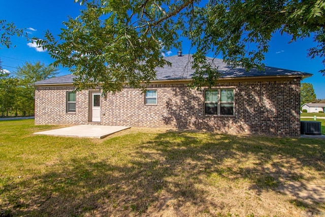 rear view of property with cooling unit, a lawn, and a patio