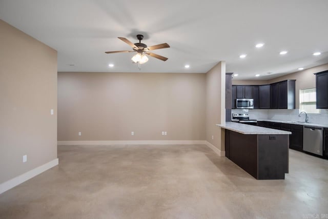 kitchen featuring light stone countertops, appliances with stainless steel finishes, sink, and ceiling fan