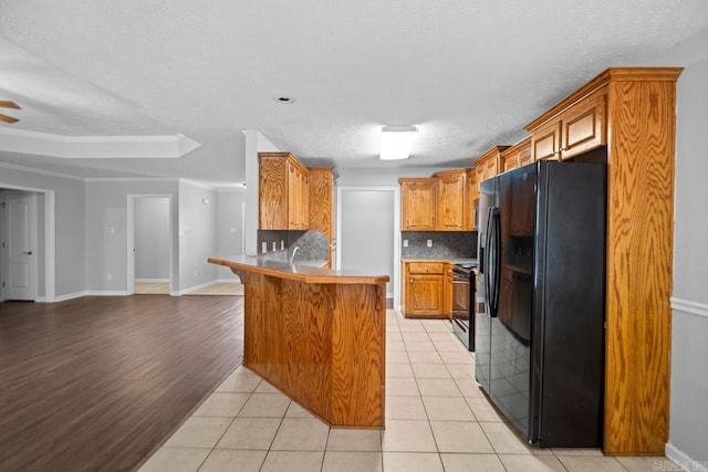 kitchen with kitchen peninsula, light hardwood / wood-style flooring, backsplash, black refrigerator with ice dispenser, and range with electric cooktop