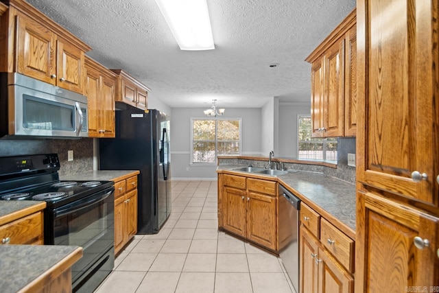 kitchen with a chandelier, sink, black appliances, light tile patterned floors, and a textured ceiling