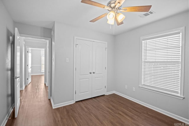 unfurnished bedroom with ceiling fan, a closet, and dark hardwood / wood-style flooring