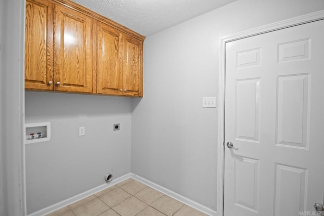 laundry area featuring hookup for a washing machine, hookup for an electric dryer, cabinets, light tile patterned floors, and a textured ceiling