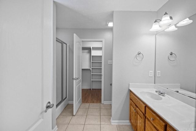 bathroom with tile patterned flooring, a shower with door, and vanity