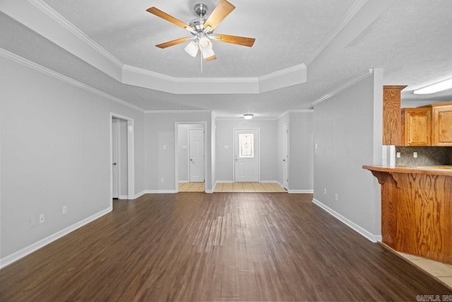 unfurnished living room with ceiling fan, a raised ceiling, dark hardwood / wood-style floors, and ornamental molding