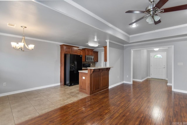 kitchen featuring black fridge, ornamental molding, kitchen peninsula, light hardwood / wood-style flooring, and a kitchen breakfast bar