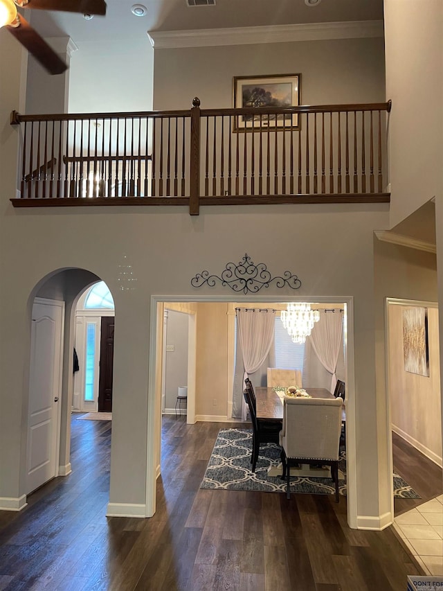 interior space featuring ceiling fan with notable chandelier, dark hardwood / wood-style floors, a high ceiling, and ornamental molding