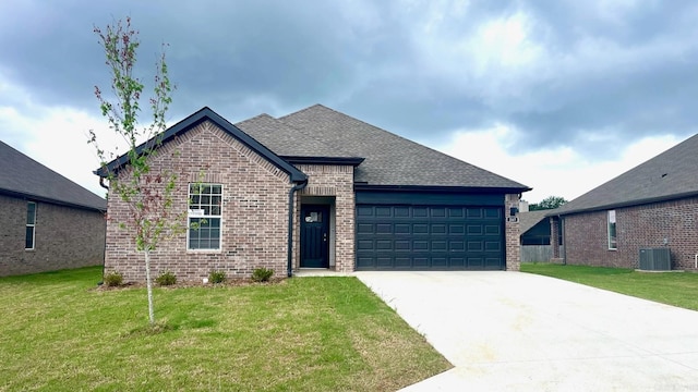 view of front of property with a garage, central AC, and a front lawn