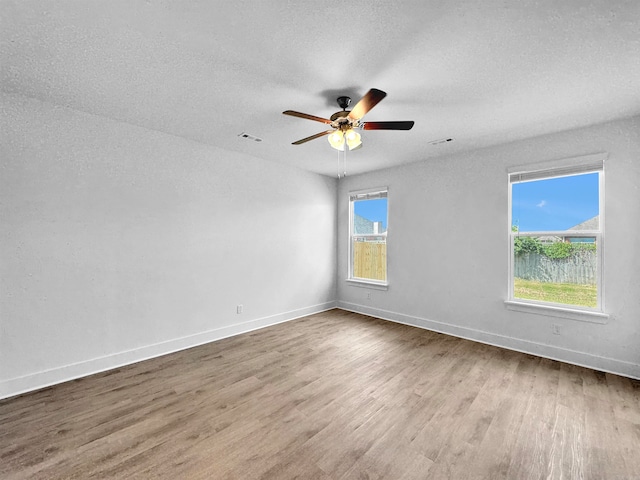 unfurnished room with ceiling fan, hardwood / wood-style floors, and a textured ceiling