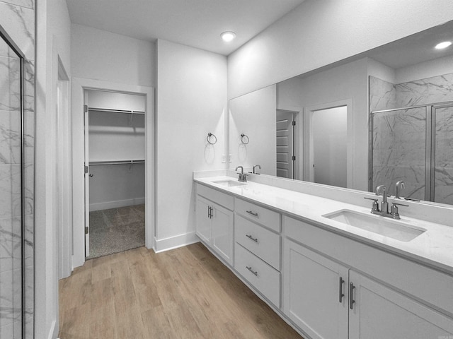 bathroom with hardwood / wood-style flooring, vanity, and a shower with door