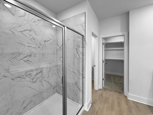 bathroom featuring a shower with shower door and wood-type flooring